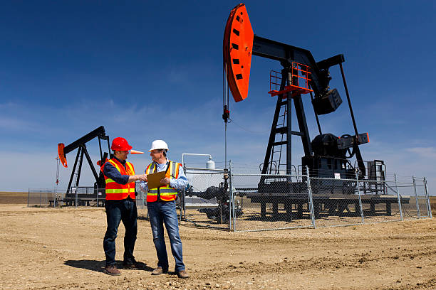 Pumpjacks and Workers An image of two oil workers at a pumpjack. oil field stock pictures, royalty-free photos & images