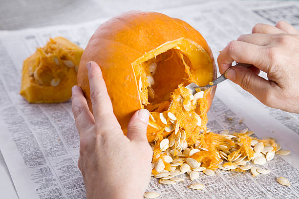 Pumpkin Carving for Halloween Hands scooping out the seeds and pulp before carving the jack o'lantern. terryfic3d stock pictures, royalty-free photos & images