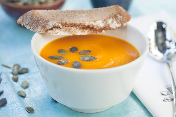 Pumpkin cream soup with seeds in a white bowl stock photo