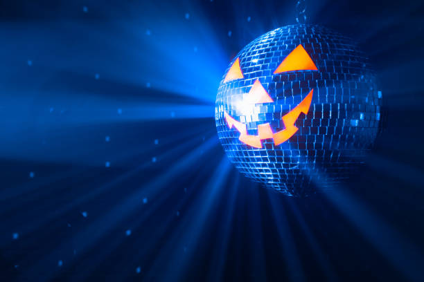 pumpkin disco ball at Halloween party, jack o'lantern with shiny rays in smoke stock photo