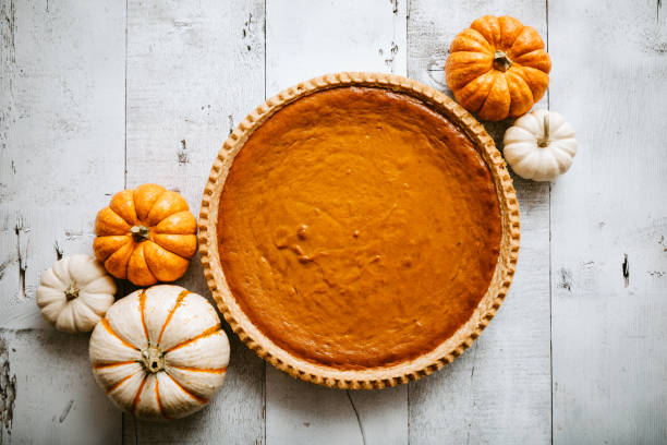 Pumpkin Pie on Rustic Background A high angle view looking down on a freshly baked pumpkin pie, just in time for your autumn or Thanksgiving season celebration.  Small decorative gourds decorate the scene.  Horizontal image with copy space. dessert sweet food photos stock pictures, royalty-free photos & images