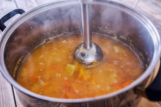 Pumpkin soup preparing, blending using stick blender stock photo