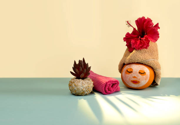 Pumpkin with facial mask and towel on pastel background with shadow from palm leaves stock photo