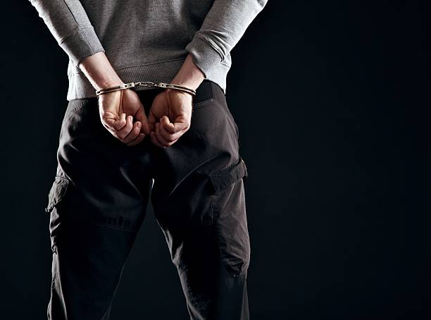 Punishment for His Crime Murderer locked in handcuffs isolated on black hands tied up stock pictures, royalty-free photos & images
