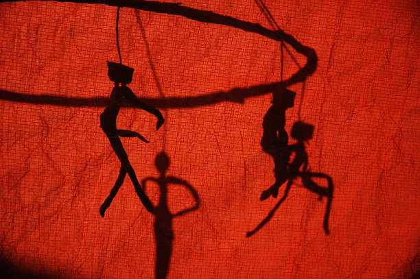 puppet shadow behind a red curtain - wajang stockfoto's en -beelden