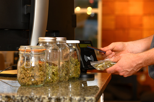 Paying by credit card for marijuana at a cannabis dispensary. Purchasing legal recreation drugs. Medical marijuana at a clinic.