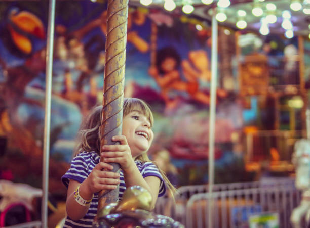 Pure Joy Happy little girl on a merry go round filled with joy carousel horses stock pictures, royalty-free photos & images