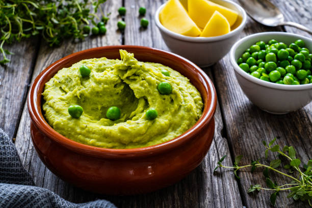 Puree - mashed potatoes with green pea in bowl on wooden table stock photo