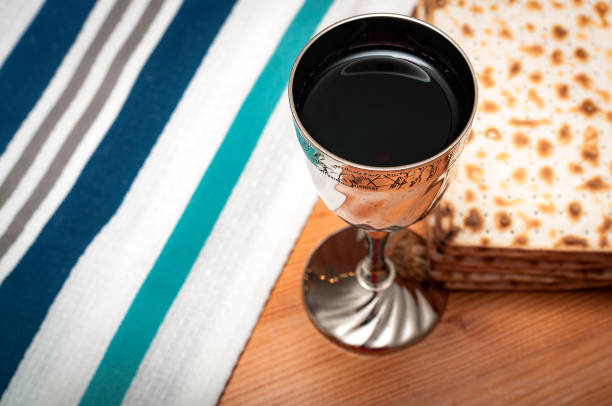 Purim jewish religious holiday and judaism Judaism and religious jewish holiday with matzos (unleavened flatbread), cup of wine, and a white and blue tallit, set up for purim or sabbath with copy space chalice photos stock pictures, royalty-free photos & images