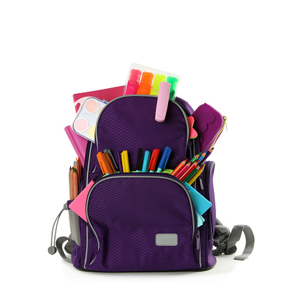 Purple backpack with different school stationery on white background