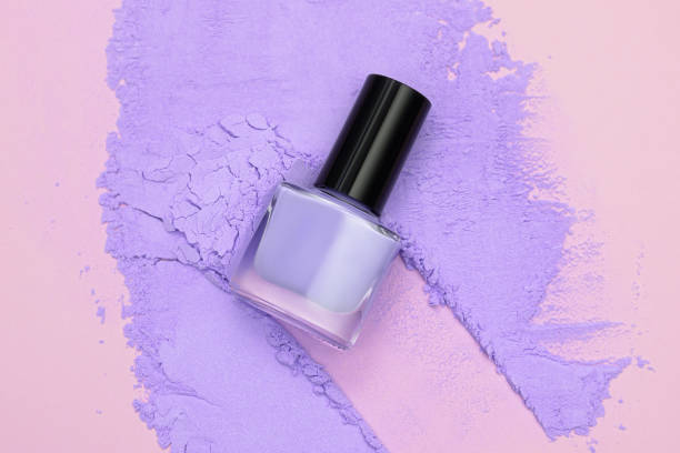 Purple nail polish bottle and purple face powder concept. Beauty products concept. Nail polish bottle top shot. stock photo