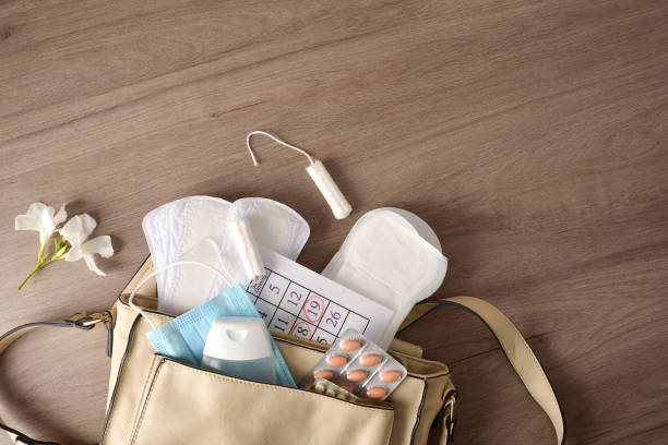 Purse with menstrual and covid-19 hygiene products top view stock photo