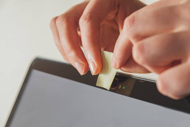Putting a piece of sticky paper on a computer webcam. stock photo