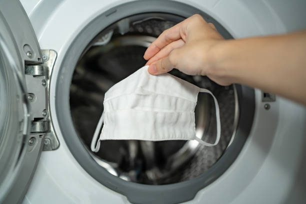 Putting cloth face mask into the washing machine stock photo