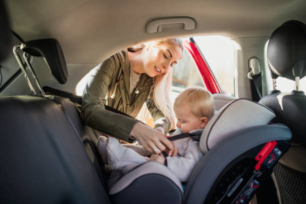 Putting Her Son in His Car Seat Young Mother putting her son in a car seat. car safety seat stock pictures, royalty-free photos & images