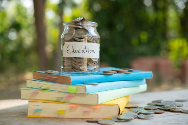 putting money coins saving in glass bottle for concept investment mutual fund finance and business, placed on the textbook. content money saving for education. stock photo