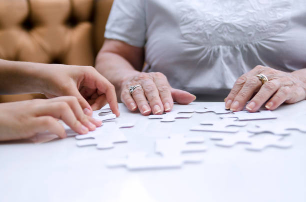 Puzzle piece in senior woman hands. stock photo