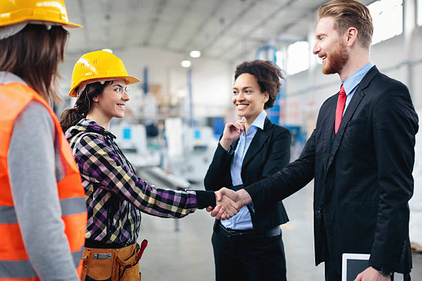 Quality inspectors shaking hands with workers stock photo