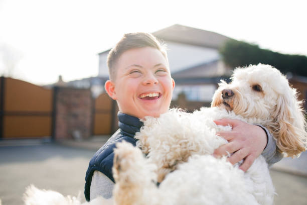 Quality Time with the Dog A boy with down syndrome hugs his pet dog in the driveway. canine animal stock pictures, royalty-free photos & images