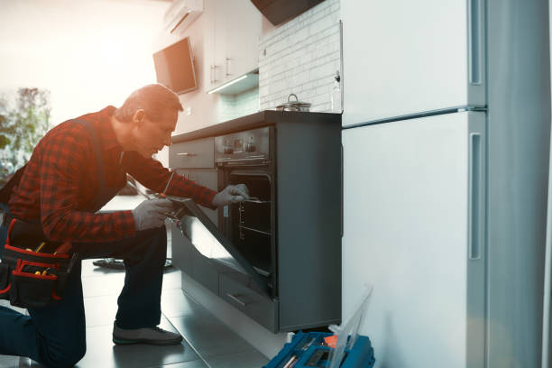 Quality work. Man solves household problems Portrait of mature man wearing tool kit standing in the kitchen, holding a screwdriver and fixing the oven door. Horizontal shot. Side view  Oven Repair Service stock pictures, royalty-free photos & images