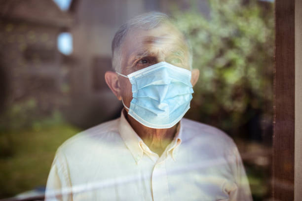 Quarantine for old people Senior man stays home because of Corona virus. He stands by the window and looks out at the garden. senior men stock pictures, royalty-free photos & images