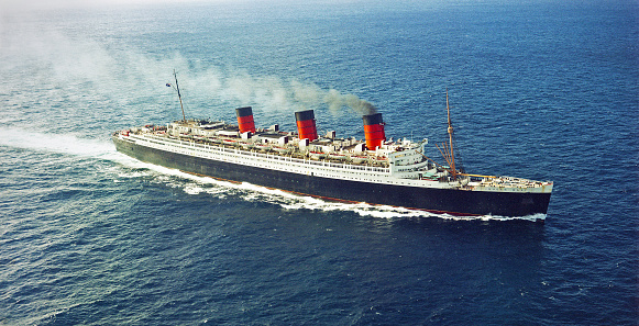 Long Beach, California, USA - December 19, 1967: Aerial view of the ocean liner RMS Queen Mary in the Pacific Ocean as she approaches Long Beach, California. The ship was retired and permanently moored in Long Beach where it still serves as a hotel, restuarants, museum and tourist attraction. Scanned film.