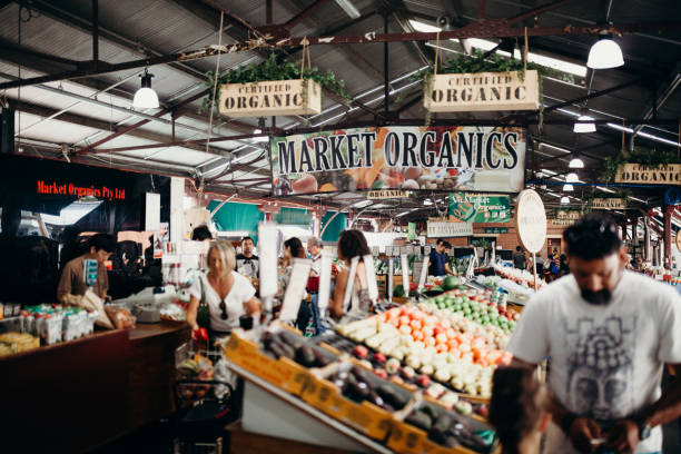 Queen Victoria market organics in the city centre of Melbourne, Australia. Melbourne, Australia - March, 11 2017:  Workers and clients walking around products in Queen Victoria Market Organic. queen victoria market stock pictures, royalty-free photos & images