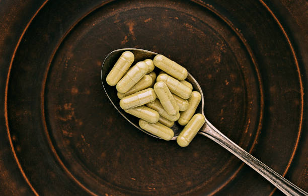 quercetin capsules on a spoon on a clay plate. mental wellbeing and personal health concept stock photo