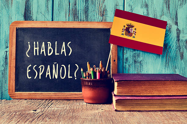 question hablas espanol? do you speak Spanish? a chalkboard with the question hablas espanol? do you speak Spanish? written in Spanish, a pot with pencils and the flag of Spain, on a wooden desk spanish class stock pictures, royalty-free photos & images