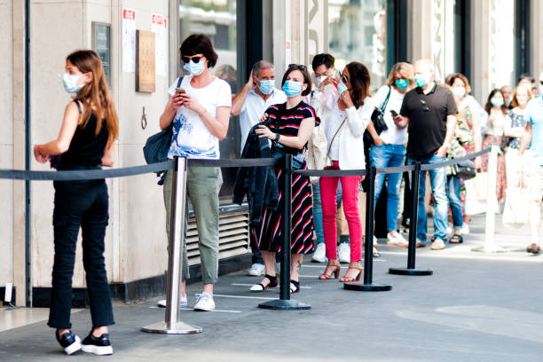 ヨーロッパのパンデミックcovid19の間、店の前に並んでいます。人々は外科用マスクを着用する必要があります。 - 行列 ストックフォトと画像