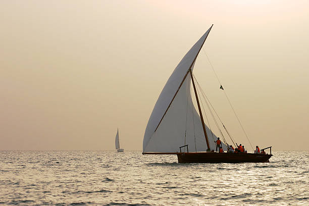 Racing Dhows Traditional racing dhows dhows at sunset in the Arabian Gulf off Dubai. dhow stock pictures, royalty-free photos & images