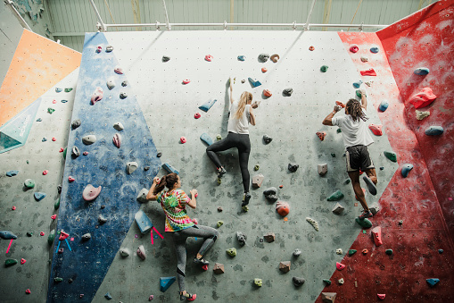 Three friends are having a race up to the top of the climbing wall.