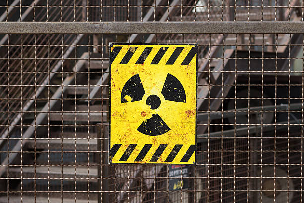radioactive warning sign on rusty fence stock photo
