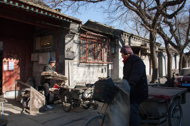 Rag collectors rides  tricycles and collect rags in a Hutong alley in a winter morning. stock photo