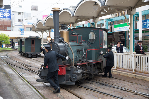 Matsuyama, Japan - April 13, 2015: Train conductors turning the Botchan Ressha steam locomotive train on a turntable at the Matsuyama City Station in Ehime Prefecture, Shikoku, Japan. 