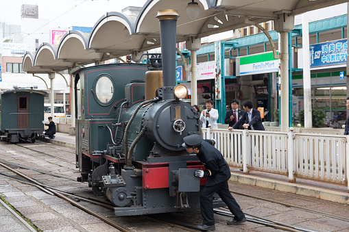 Matsuyama, Japan - April 13, 2015: Train conductors turning the Botchan Ressha steam locomotive train on a turntable at the Matsuyama City Station in Ehime Prefecture, Shikoku, Japan. 