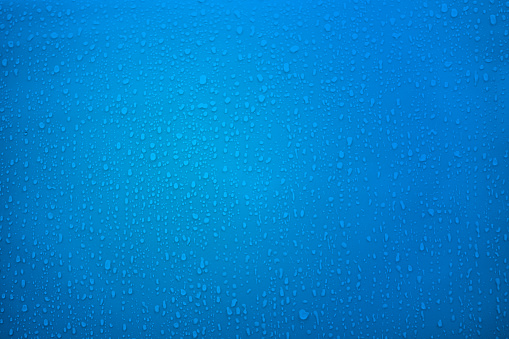 Rain drops on blue metal background close-up. Water drops blue texture