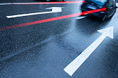 istock Rain wet asphalt road, arrows and motion blurred car 1079113124