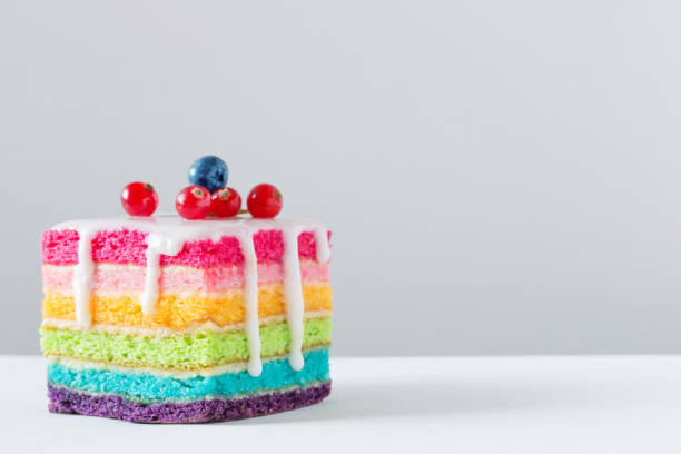 regenbogen kuchen auf weißem hintergrund - kuchenstück stock-fotos und bilder