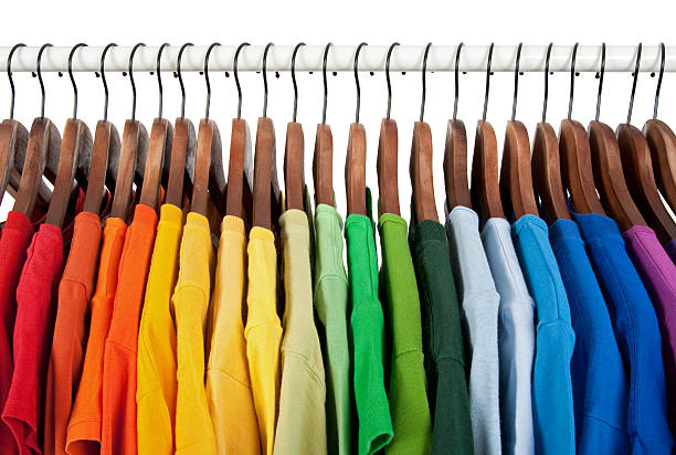 Rainbow colors, clothes on wooden hangers Rainbow colors. Choice of casual clothes on wooden hangers, isolated on white. clothes rack stock pictures, royalty-free photos & images