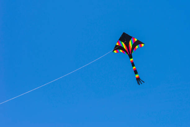 A rainbow colors kite (delta shape) flying in the blue sky stock photo