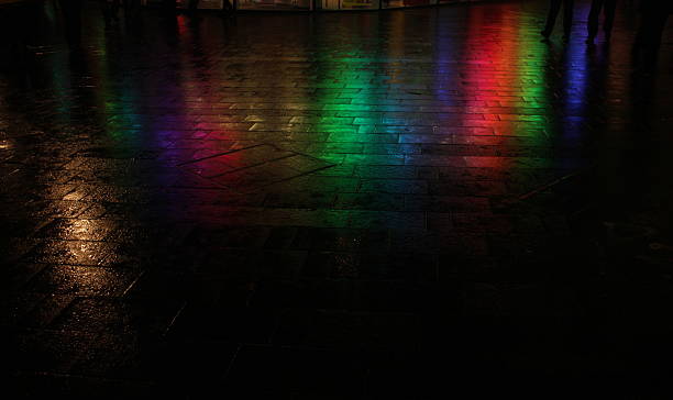 Rainbow colors reflected on wet street at night stock photo