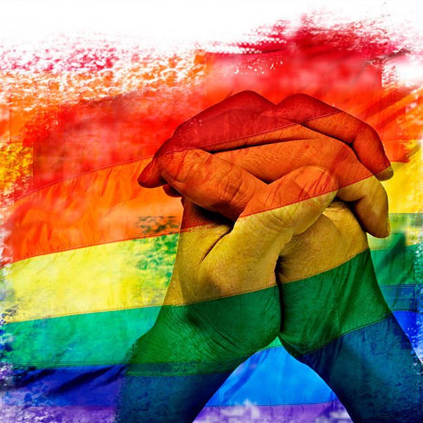 bandeira do arco-íris e homem mãos de oração - homofobia - fotografias e filmes do acervo