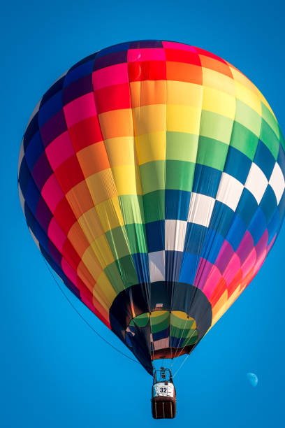Rainbow hot air balloon flying through the sky at an air show in Battle Creek Michigan stock photo