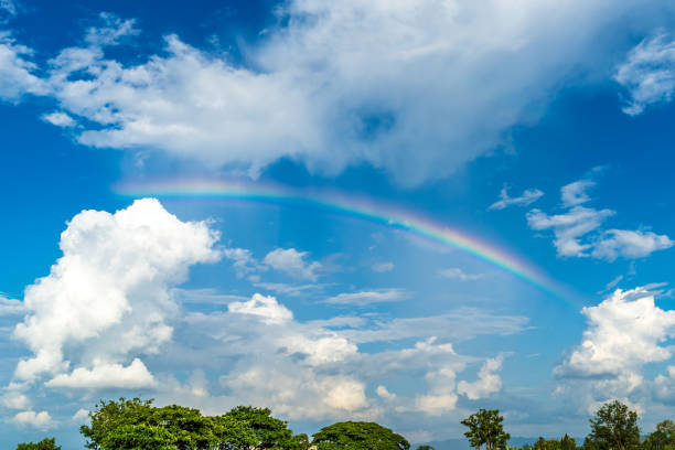 rainbow in blue sky stock photo