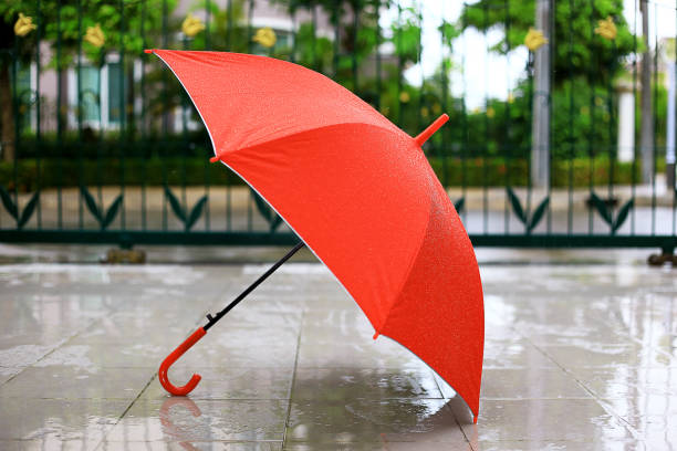 Raining drops falling to a red color umbrella at flooring background. stock photo
