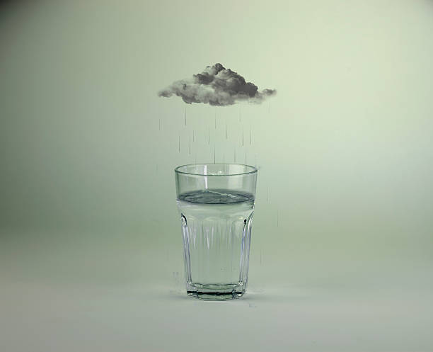 Raining into glass of water stock photo