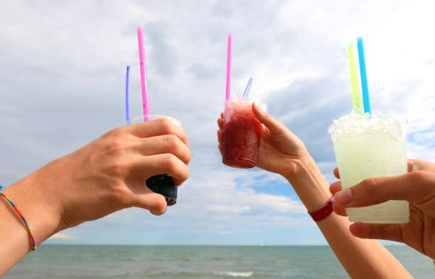 raised hands with an iced grenadine and fruit syrup for a toast to celebrate the summer holidays stock photo
