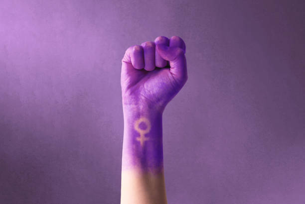 Raised purple fist of a woman for international women's day and the feminist movement. March 8 for feminism, independence, freedom, empowerment, and activism for women rights stock photo