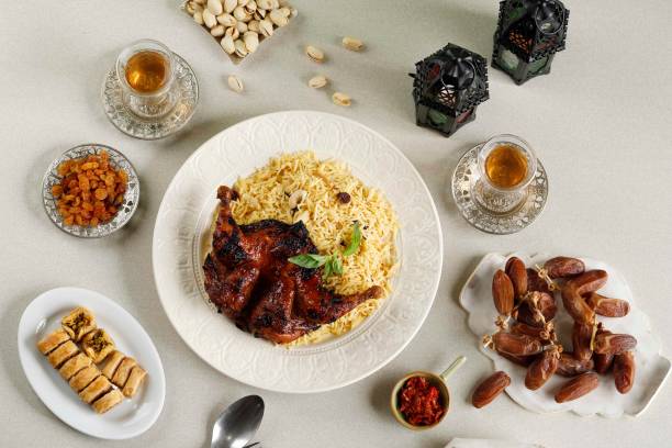Ramadan Iftar Menu, Basmati Rice Kabsa with Roasted Chicken, Raisin, Tea, Dates Fruit, Pistachio, and Turkish Baklava stock photo